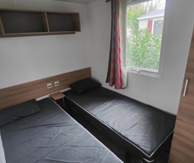 Chambre avec deux lits simples et fenêtre dans le mobile-home Les sables du midi