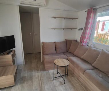 Salon avec canapé et télévision dans le mobil-home Les sables du midi