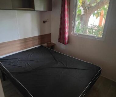 Chambre avec lit et fenêtre dans le mobile-home Les sables du midi