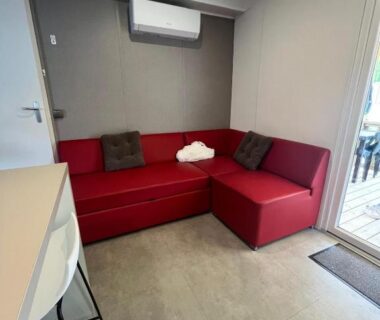 Salon avec canapé d'angle rouge et climatisation dans le Mobile Home 6 personnes