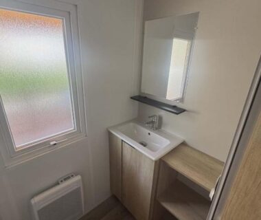 Salle de bains avec lavabo miroir et rangements dans le Mobile Home 8 personnes