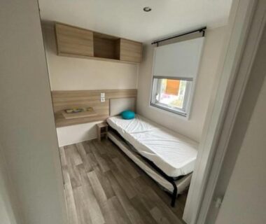 Chambre simple avec lit, fenêtre et rangements dans le Mobile- Home AMIRA