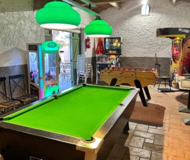 Salle de jeux intérieure avec billard babyfoot et bornes d'arcade au Camping Le Dattier