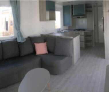 Salon avec canapé d'angle kitchenette et coin repas du Mobile Home La Roulotte Catalane