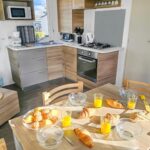Cuisine avec table dressée croissants et jus dans le Mobile Home Luca – Séjour Nature