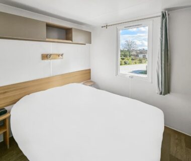 Chambre avec lit double et fenêtre sur piscine du Mobile Home Luca
