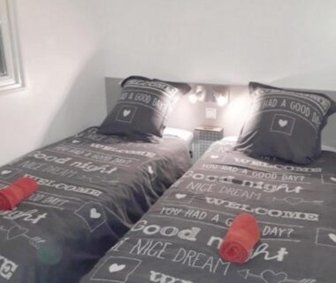 Chambre avec deux lits simples et serviettes rouges du Mobile Home Service Hotelier