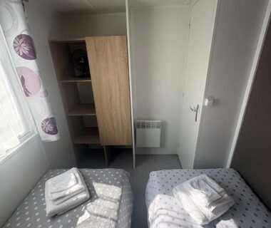 Chambre avec deux lits jumeaux armoire fenêtre et serviettes dans le Mobile Home XL Camping 5 étoiles