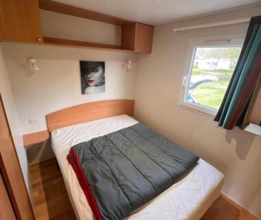 Chambre avec lit double et fenêtre donnant sur le camping dans le Mobile Home à Louannec