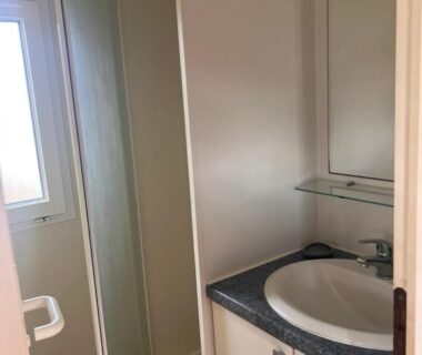 Salle de bain avec lavabo et douche dans le Mobile Home à Louannec