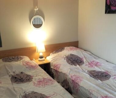 Chambre avec deux lits et lampe dans le Mobile Home à Louannec