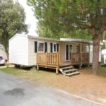 Emplacement de camping avec terrasse en bois et arbres du Mobile Home bois dormant