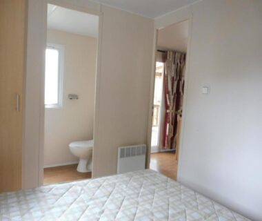 Chambre avec lit et salle d'eau du Mobile Home bois dormant