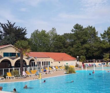 Piscine extérieure du camping avec transats et bâtiment en arrière plan au Mobile Home bois dormant