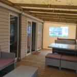 Terrasse couverte avec banquettes et table dans le mobile home du Domaine de Kerlann