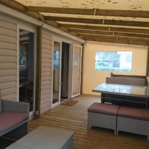 Terrasse couverte avec banquettes et table dans le mobile home du Domaine de Kerlann