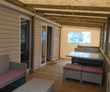 Terrasse couverte avec banquettes et table dans le mobile home du Domaine de Kerlann