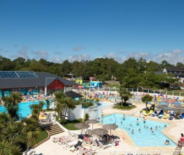 Piscine extérieure avec toboggans palmiers et transats au Mobile Home dans Domaine de Kerlann