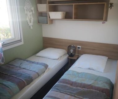 Chambre avec deux lits simples et étagères dans le Mobile Homes Sous le Soleil