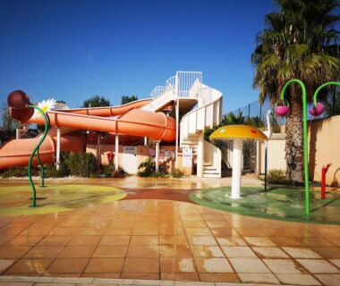 Espace piscine ludique avec toboggan et jets d'eau au camping Mobile Homes Sous le Soleil
