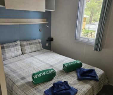Chambre avec lit double serviettes vertes pliées et fenêtre dans le Mobile Homes by KelAir at Camping La Yole