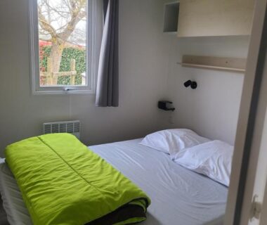 Chambre avec lit double fenêtre et couette verte dans le mobile home