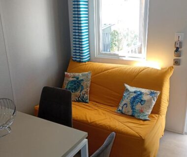Intérieur avec canapé jaune et coussins près de la fenêtre du mobile home