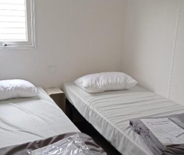 Chambre avec deux lits près de la fenêtre dans le mobile home
