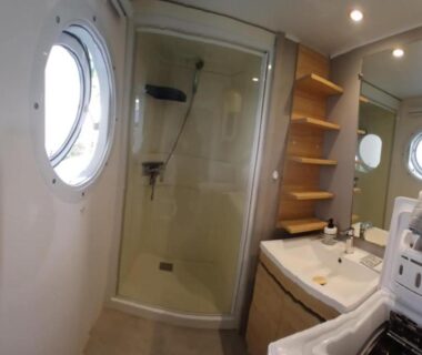 Salle de bains avec douche hublot et lavabo dans le Mobile home