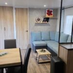 Intérieur avec canapé bleu et coin repas du Mobile home 4 a 6 personnes Domaine de Kerlann