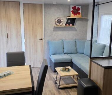 Intérieur avec canapé bleu et coin repas du Mobile home 4 a 6 personnes Domaine de Kerlann