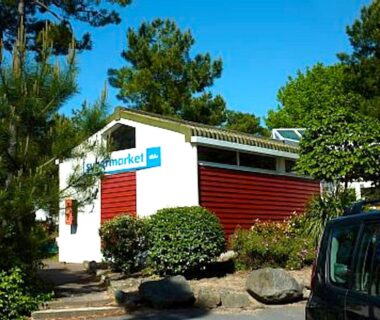 Allée et bâtiment du market au camping entourés d'arbres Mobile home