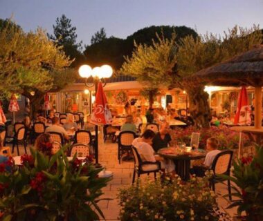 Terrasse extérieure éclairée avec tables et parasols au Mobile home 5-pers Camping Leï Suves-Côtes d'Azur-including airco