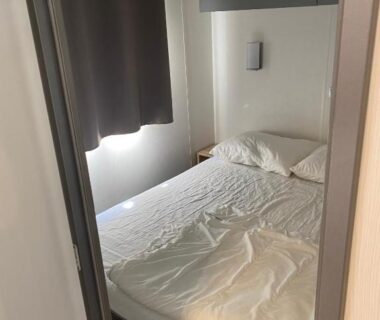 Chambre avec lit et rideau dans le mobile home 5-pers Camping Leï Suves Côtes d'Azur including airco