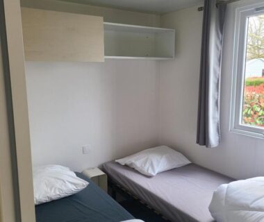 Chambre intérieure avec lits simples et fenêtre dans le mobile home