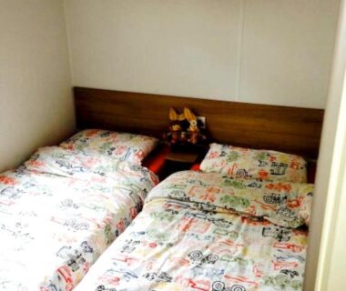 Chambre avec deux lits et table de chevet fleurie dans le mobile home