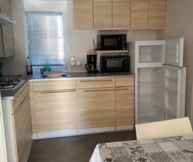 Cuisine équipée avec réfrigérateur ouvert et table dans le mobile home 6 personnes à Munster