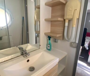 Salle de bain avec lavabo miroir et sèche-cheveux dans le mobile home 6personnes à Munster