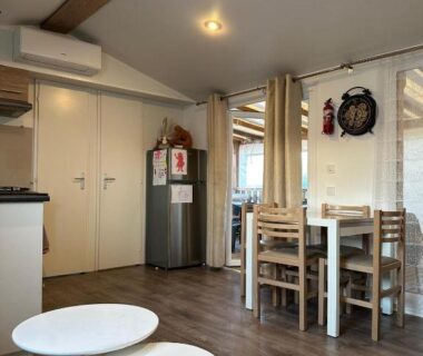 Séjour avec table chaises et kitchenette dans le mobile home Harley