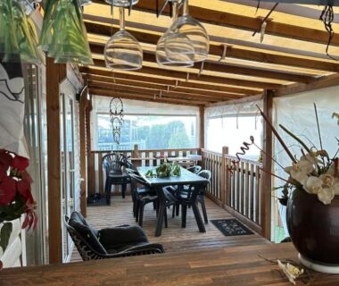 Terrasse couverte avec table chaises et verres suspendus dans le mobile home Harley