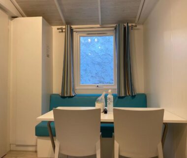 Coin repas intérieur avec table banquette et chaises du Mobile home Premium 24m² 2 chambres