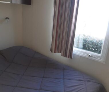 Chambre avec lit double et fenêtre dans le mobile home S004