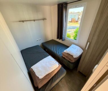 Chambre avec deux lits simples et serviettes pliées dans le mobile home Sol a gogo