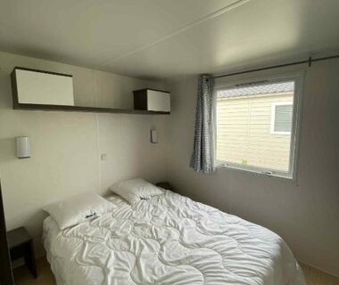 Chambre double avec lit et fenêtre dans le mobile home à Mimizan