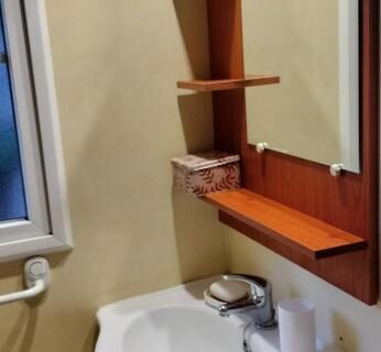 Salle de bain avec lavabo miroir et étagères dans le mobile home camping Ardèche