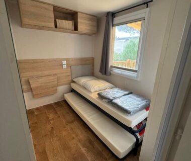 Chambre avec deux lits et fenêtre dans le Mobile home canet en Roussillon
