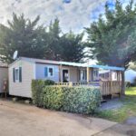 Terrasse et façade du mobile home avec haie au camping Mobile home climatisé