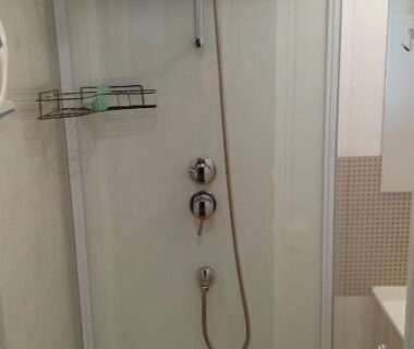 Cabine de douche avec pommeau flexible et étagère dans le mobile home climatisé