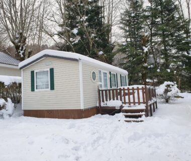 Extérieur enneigé avec mobile-home et terrasse du mobile-home confort 3 chambres au camping La Bourboule