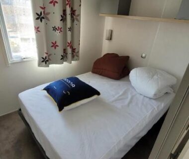 Chambre avec lit double et fenêtre dans le mobile-home confort 3 chambres au camping La Bourboule